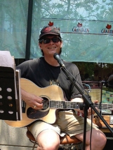 Mark sitting,smiling and playing guitar