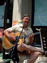 Eric sitting,smiling and playing guitar